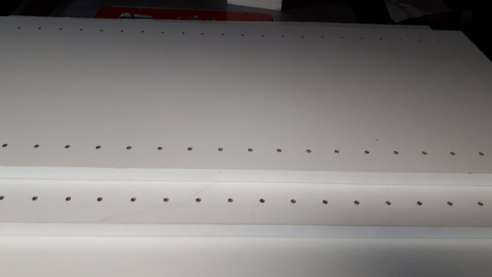 Vit platta med flera rader av noggrant frästa hål.