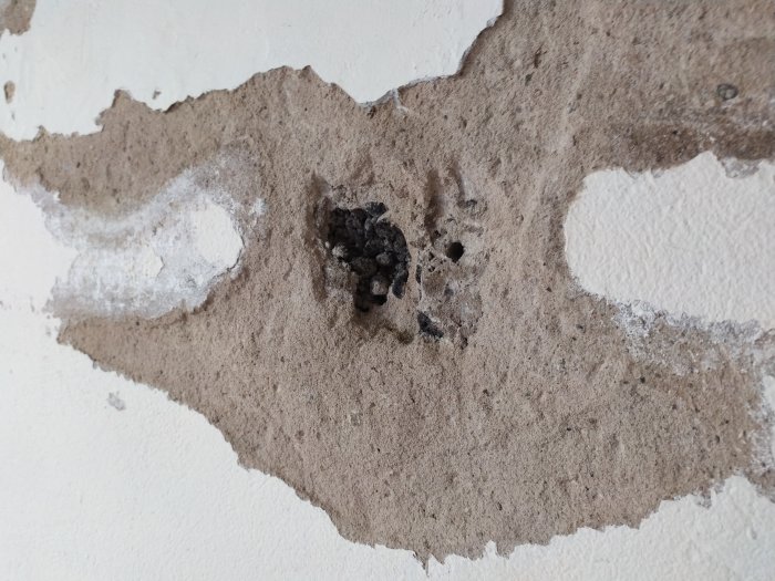 En skadad putsad vägg med Lecablock där putsen har lossnat och exponerat stenen under.