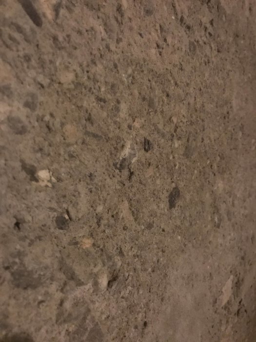 Närbild av en grov betongvägg med synliga stenpartiklar och ojämn textur.