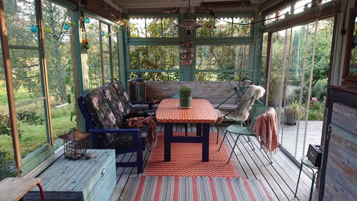 Inglasad altan med återbrukade möbler, färgglada mattor och utsikt över trädgården.