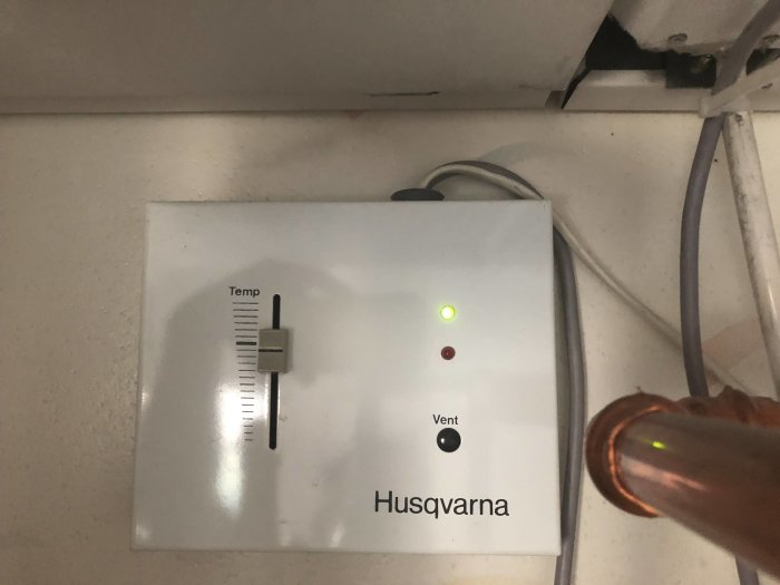 Husqvarna termostatpanel för FTX med en justerad temperaturvred och två indikeringslampor.