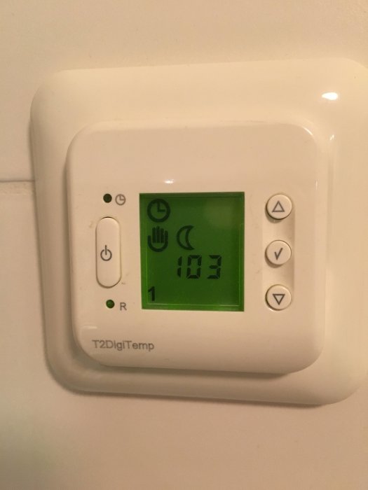 Termostat för golvvärme med digital display som visar 10.3 grader, knappar och en tänd lampa.