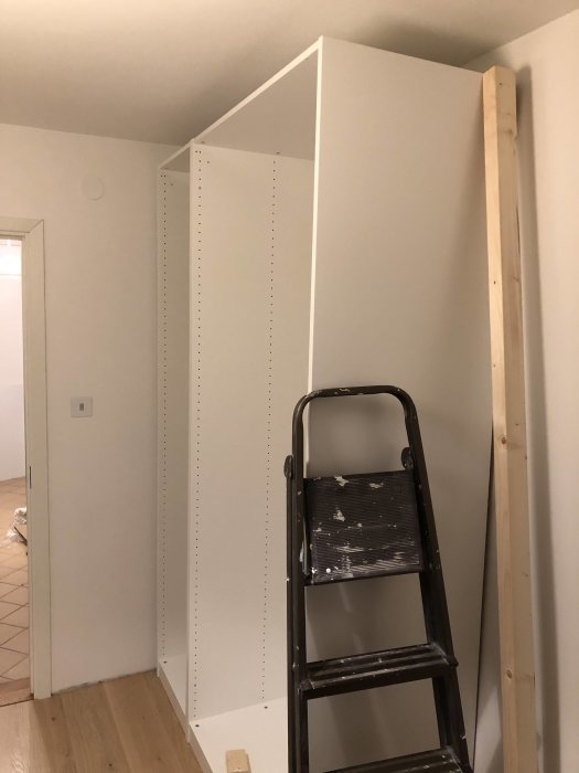 Inbyggnad av vit Pax-garderob bredvid en stegpall i ett rum under renovering.