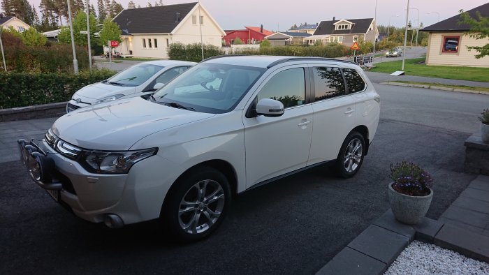 Vit polerad bil parkerad framför hus med blank och reflekterande lack efter behandling.