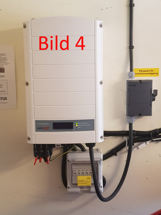 Solaredge växelriktare och elmätare installerade på vägg med ledningar och anteckningar.