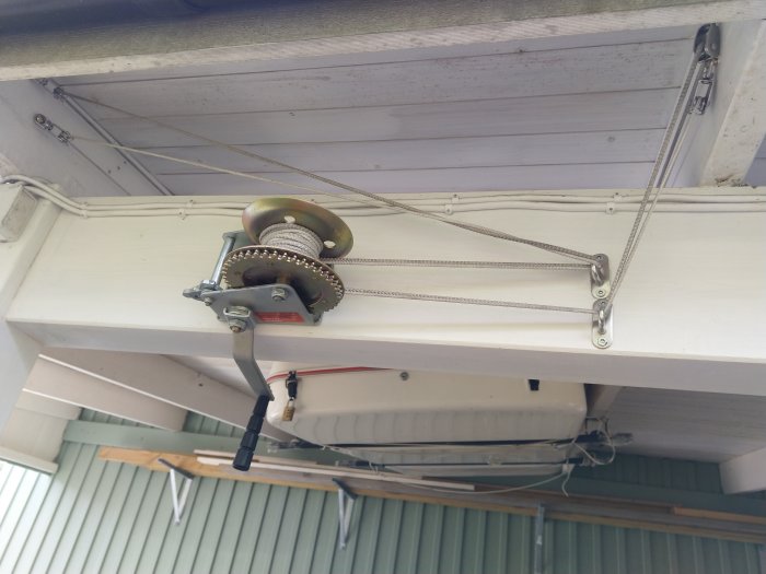 Wire winch och blocksystem monterade under en carport för att hissa en takbox.