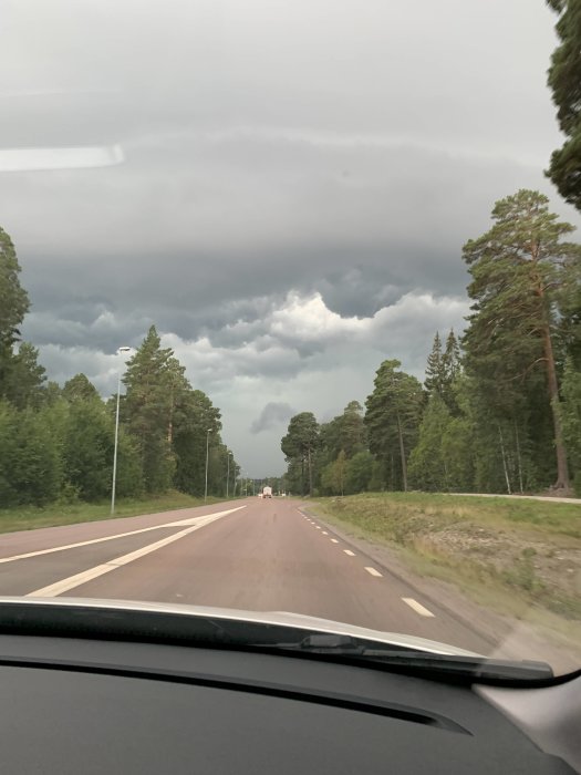 Vy från bil på motorväg med mörka moln som tyder på ett kommande regnväder.