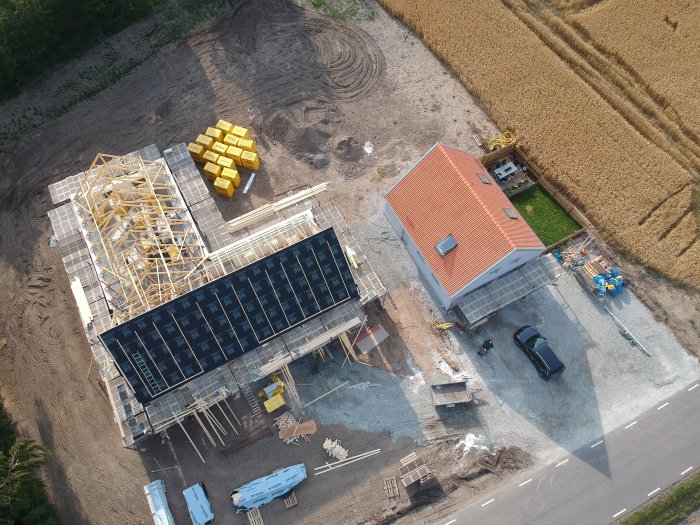 Luftbild av en pågående huskonstruktion med trästomme och ett närliggande färdigt hus.