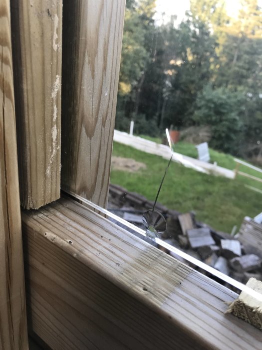 Reparerat fönsterglas med en knappt synlig spricka nära fönsterkarmens träram.