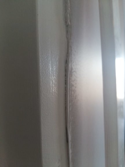 Glipa mellan en vitmålad dörrkarm och ojämnt tapetlager som föreslår en monteringsutmaning vid renovering.