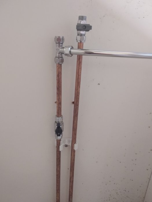Installation av kopparledningar med vattenmätare och anslutningar på en vägg.