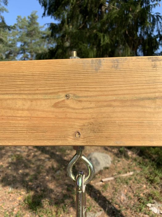Träplanka på 45x120 fäst vid metallögla med surrning utan skruvar, i naturlig miljö.