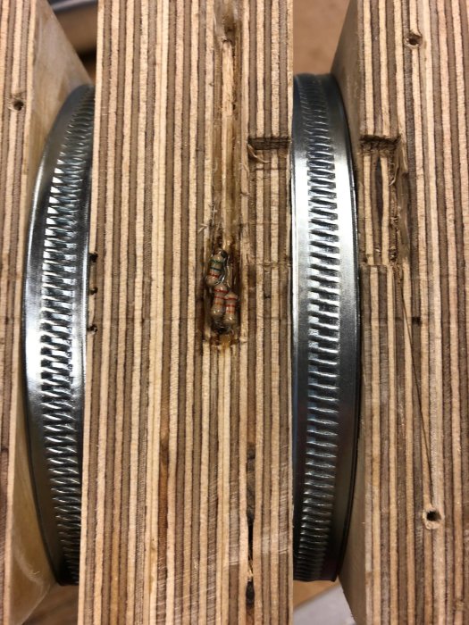 Skadade träbitar med urfrästa spår och elektroniska komponenter, troligen relaterat till en CNC-fräsprocess.