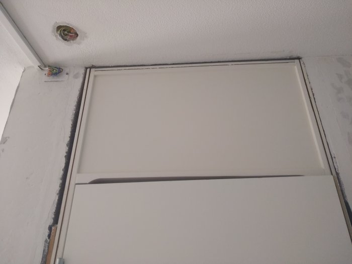 Träpanel över dörr med synligt utrymme till betongvägg redo för renovering.