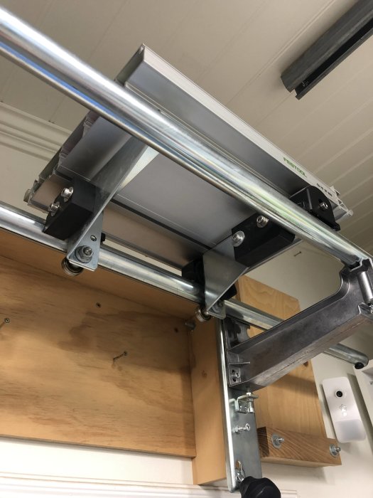 Metalljusterbord med monterade stödklackar i polyamid under träskiva, sedd från underifrån.