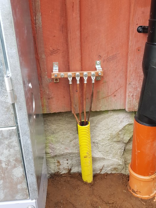 Jordningssystem för hobbyinstallation av solceller med kopparledare monterade på en stolpe och isolerade i gult rör vid marken.