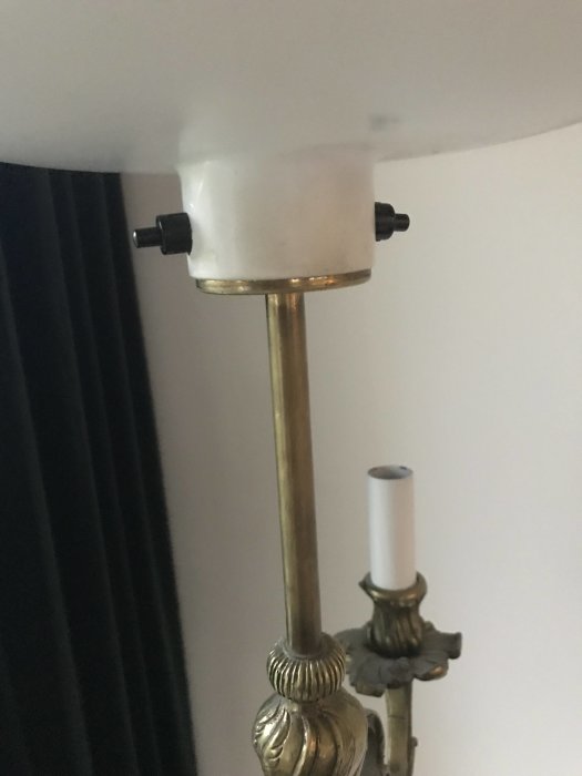 Närbild av en lampsockel med en glödlampsadapter och en del av lampstommen i mässing.