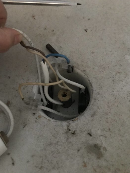 En öppen golvuttagdosa med synliga elkablar och anslutningen, under installationsprocessen.