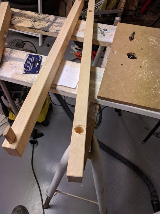 Trädelar med ett borrat hål på en arbetsbänk under tillverkning av en anpassad grind.