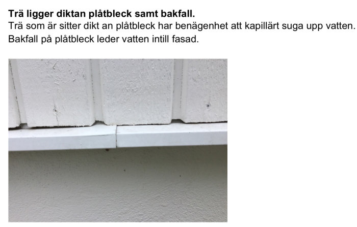 Skadat trä nära plåtbleck på fasad med tecken på vattenskada och kapillär uppsugning.