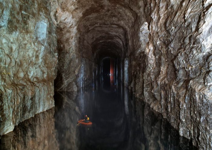 En person som paddlar kajak i en upplyst underjordisk grotta.