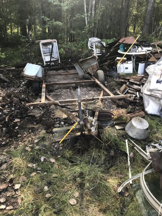 En övergiven och nedbruten husvagn bland högar av skräp i skogen.