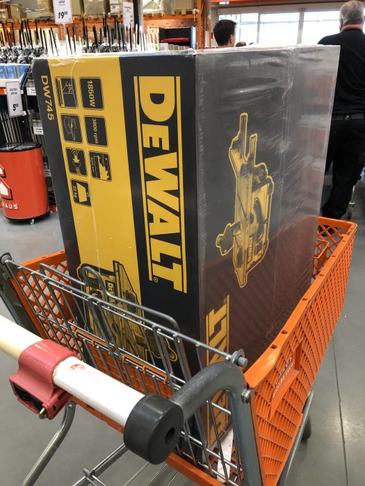 En förpackad DeWALT-produkt i en orange kundvagn inne i en bygghandel.