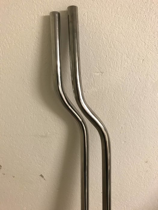 Två metallrör bockade i S-form mot en vit vägg, förberedda för montering vid elementinstallation.
