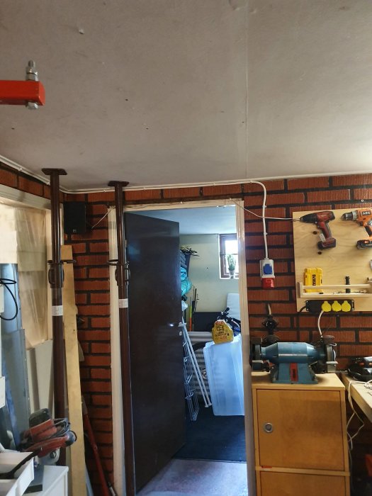Elledningar förlagda längs taket och väggen i ett arbetsrum med verktyg och byggmaterial.