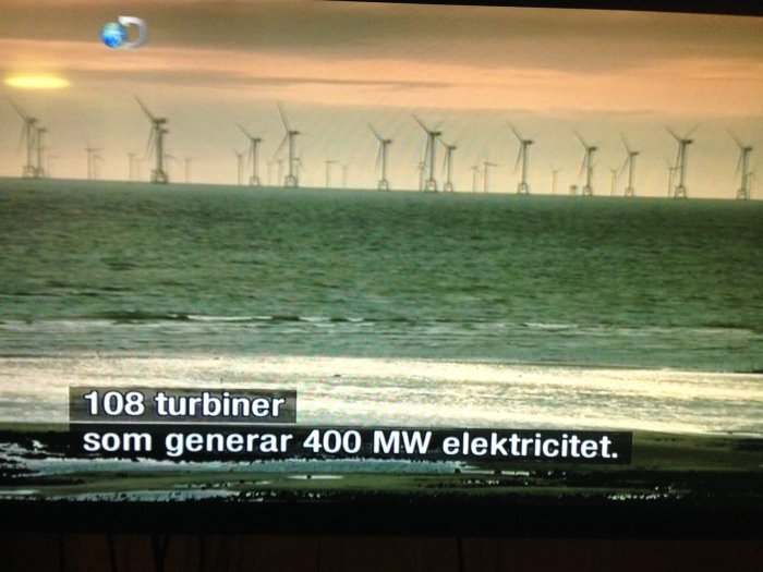 Vindkraftspark i havet med flera vindturbiner och text som indikerar "108 turbiner som genererar 400 MW elektricitet".