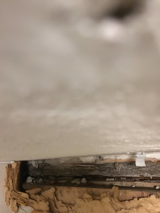 Rakentamisen viistokulmassa näkyy seinäpalkki. Pinta on tumma ja ja epätasainen alhaalta, kuvattu kellarista käsin.