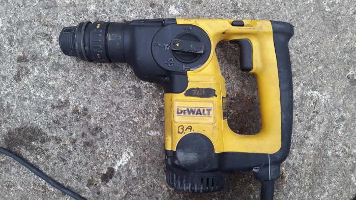 Begagnad DeWalt borrhammare D25304K med spår av olja på sidan och vid ventilationsgallret.