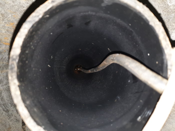 Översikt av en öppen brunn med synlig elkabel som går ner i ett centralt borrat rör.