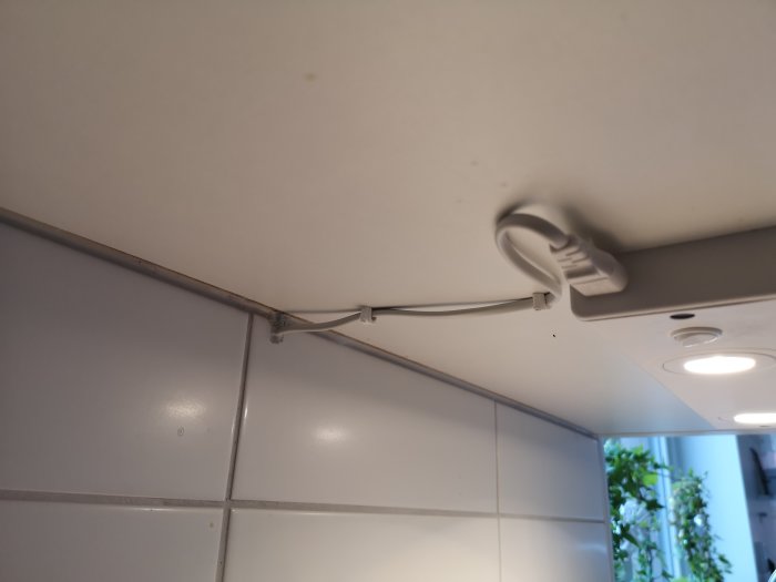 Elsladd med stickkontakt ovanför köksbänk mot vit kakelvägg, ifrågasatt installation.