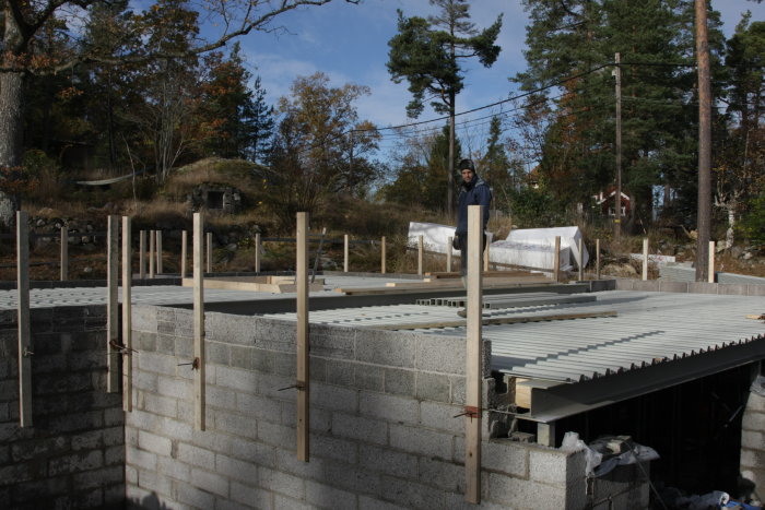 Byggarbetsplats med formvirke och person som förbereder gjutning av bjälklag med samverkansplåtar över garage.