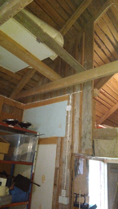 Takbjälkar i trä i ett orenoverat loft med en balk som skapar ett hinder.