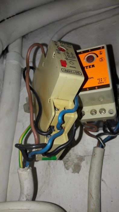 En trappautomat från Landis & Gyr monterad med synliga elektriska kablar och rör.