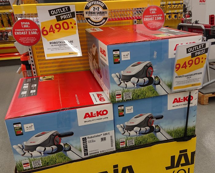 AL-KO Robolinho 500 E robotgräsklippare i förpackningar på butikshylla med prisskyltar.