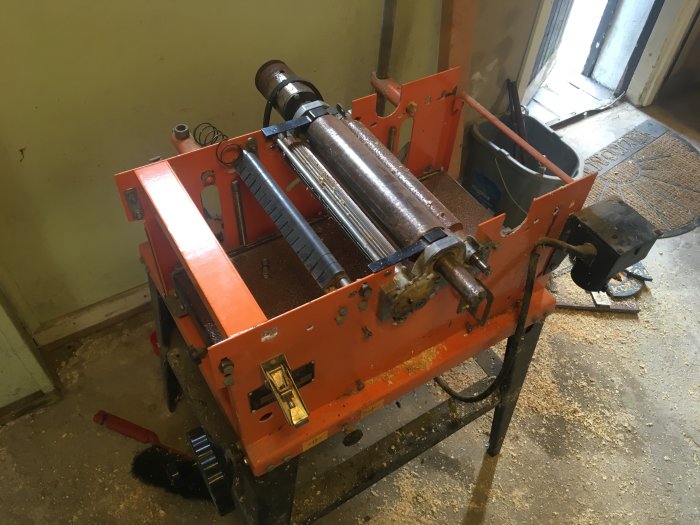 Orange kombimaskin REMA DYMC-8 med synlig rost och spån i demonterat skick i ett verkstadsutrymme.