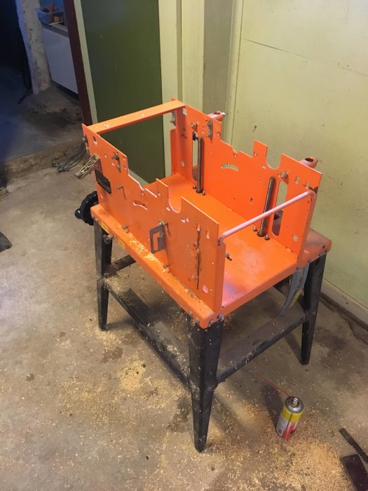 Demonterad orange och svart kombimaskin REMA DYMC-8 med synliga komponenter och träspån omkring.