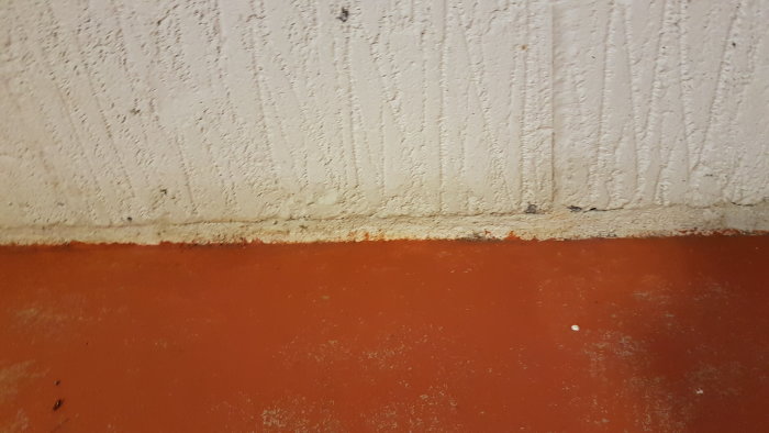 Vägg och golv möts i byggprojekt, inga synliga tecken på fukt vid skarven.