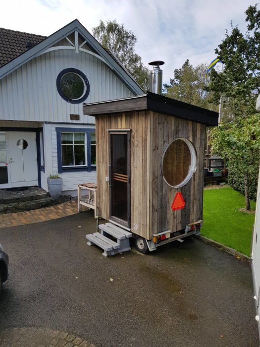 Portabel bastu byggd på en släpkärra parkerad framför ett hus.