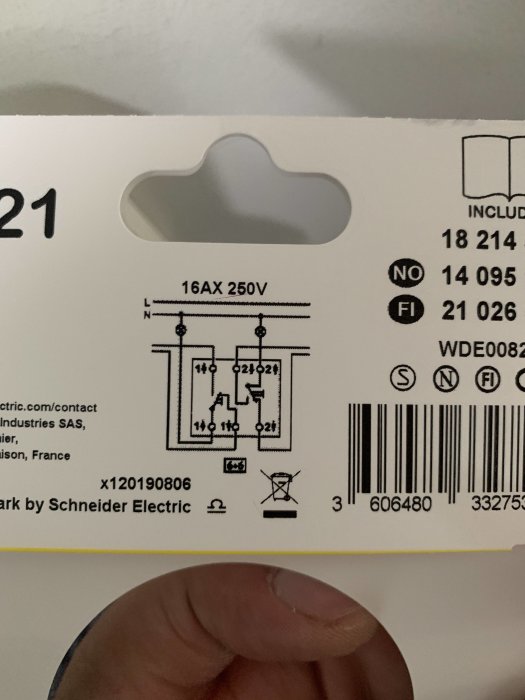 Hand som håller en Exxact Primo strömställarask med elektriskt schema.