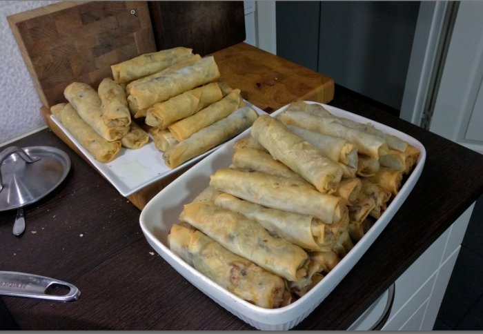 Hemlagade rullar fyllda med grönsaker på en vitbricka och i en vit skål på ett köksbord.