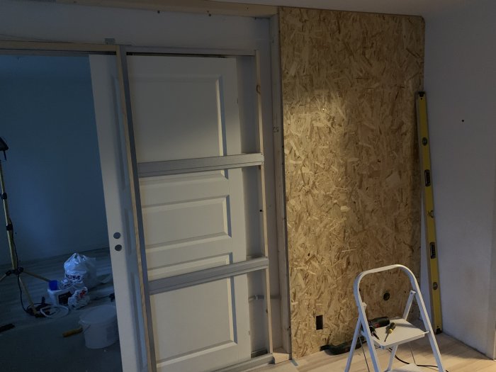 Installation av pocketkarm i spelrum med oskyddad OSB-vägg, öppen dörr och arbetsmaterial.