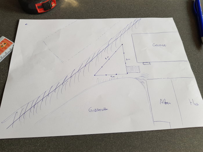Handritad skiss av en tomtplan med triangelformat förråd, hus, garage och allé markerade, inklusive måttangivelser.