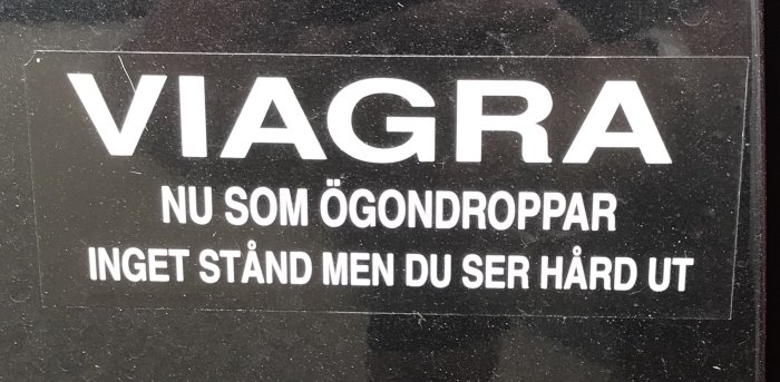 Dekal med texten "VIAGRA NU SOM ÖGONDROPPAR INGET STÅND MEN DU SER HÅRD UT" på en bilruta.