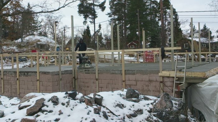 Byggarbetsplats med bjälklag gjutet, provisorisk bro och person som arbetar på byggnadsställning.