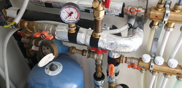 Installation av radiatorsystem med mätare, ventiler och isolerade rör.