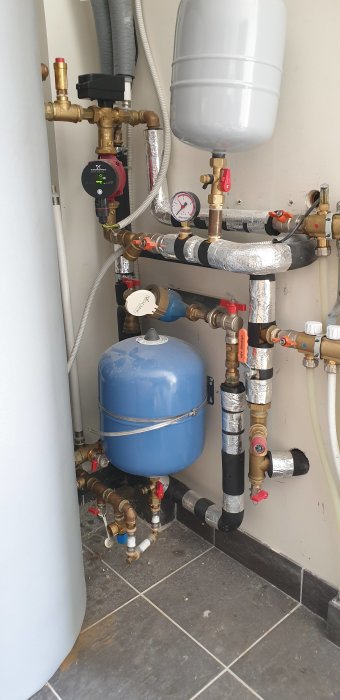 Installation av radiatorsystem med expansionskärl, rör, ventiler och mätare i ett pannrum.